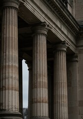 Naklejka premium Tall, fluted stone columns supporting a massive stone architrave. Classical architecture detail displaying age, strength, and durability ,column ,detail ,aged