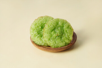 A traditional kue cucur is placed on a wooden plate against a cream background