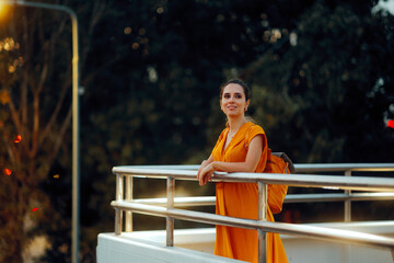 Happy Woman Wearing an Yellow Dress and a Matching Backpack. beautiful lady feeling relaxed while walking in the city
