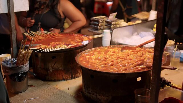 Spicy tteokbokki and odeng cooking in large pots at a bustling Korean night market