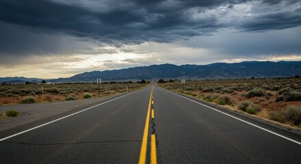 Naklejka premium Empty country road intersection at the roadside leading to distant mountains under a wide, dramatic sky, suggesting travel and decision ,roadside ,infrastructure ,mountain