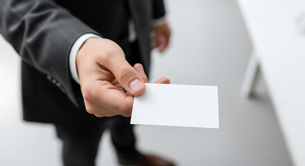 Close up of a businessmans hand extending a blank white business card for networking.