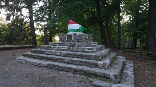 Stone monument marking the K&eacute;kestető peak, the highest point in Hungary at 1014 meters, featuring a rock painted in the colors of the Hungarian flag and surrounded by the M&aacute;tra forests.