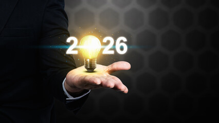 Business hand showing 2026 with a bright light bulb. Happy New Year concept or Celebration
