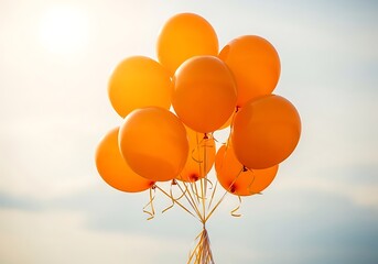 A cluster of vibrant orange balloons float against a softly blurred bright background