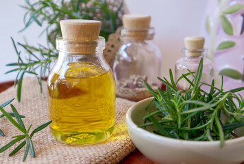 Rosemary herbal essential oil on the natural background with fresh rosemary twigs