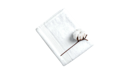 White folded towel with a single cotton boll laying diagonally atop, shot on a plain dark background