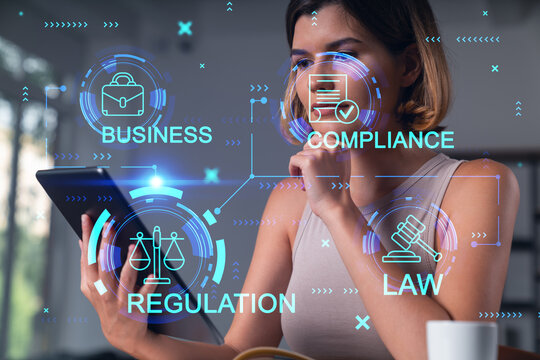Smiling businesswoman in casual wear holding tablet device touching it at office workplace. Concept of distant work, business education, information technology. Law and order icons hologram