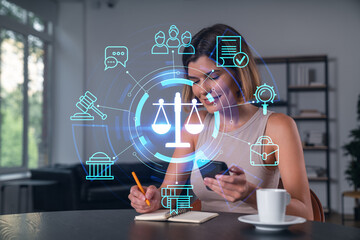 Smiling businesswoman in casual wear holding using smartphone typing at office workplace with notebook. Concept of distant work, business education. Law and legal theme icons hologram