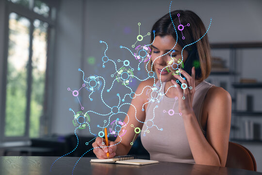 Smiling businesswoman in casual wear holding using smartphone typing at office workplace with notebook. Concept of distant work, business education. Ai icons hologram