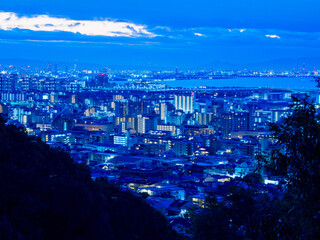 夜明け前の神戸市街地と大阪湾を隔てた大阪の市街地