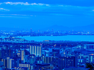 夜明け前の神戸市街地と大阪湾を隔てた大阪の市街地