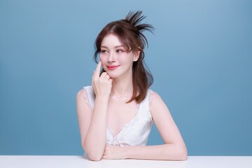 Asian woman model with natural makeup on face clean fresh skin on isolated blue background.