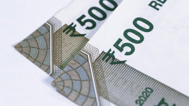 Close up view of two 500 Indian rupee bank notes rotating on white background, business concept.