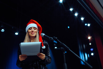 Happy Woman Presenting a Christmas Show on Stage. female presenter making a speech on stage during Xmas event
