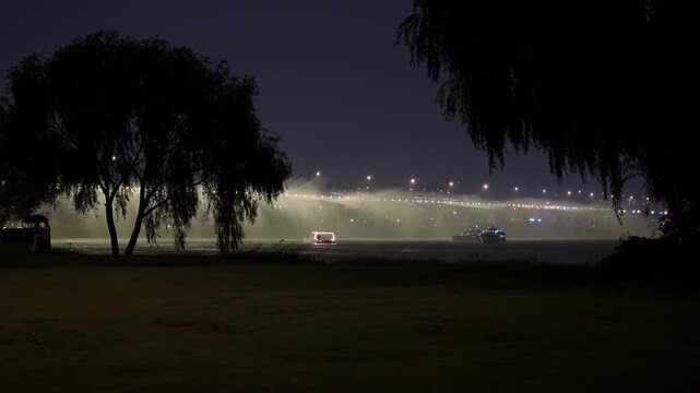 Han River view presenting the illuminated fountain from Banpo Bridge with trees in the foreground