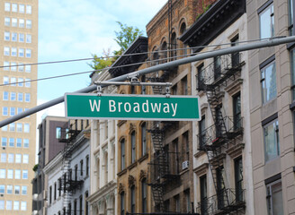 Fototapeta premium road sign hanging in the middle of a new york intersection with text W Broadway