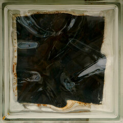 single closeup of a dark transparent glass tile in a vintage window