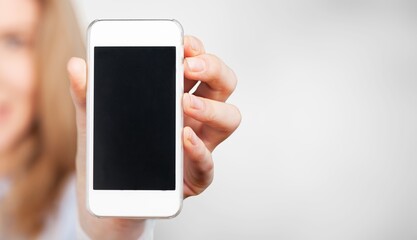 Smiling young woman hold mobile phone with blank screen