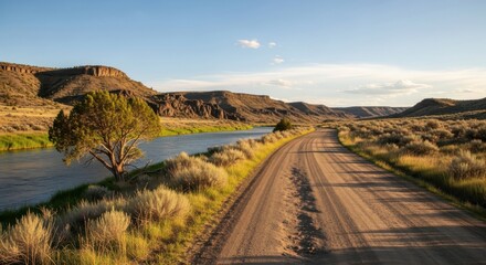 Golden hour light bathes a scenic desert road winding alongside a serene river and rugged mountains, inviting adventure and exploration.
