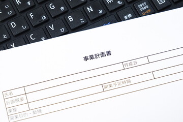 事業計画書 - 新規事業の立ち上げに先立ち、事業計画書を作成する起業家のイメージ
