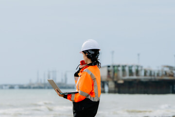 A woman wearing an orange safety vest. Female engineer or supervisor in PPE at an industrial site (petrochemical plant, refinery, or shipping port)
