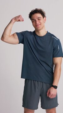 Face, man and flex bicep for fitness progress, exercise results or smile with wellness in studio. Portrait, show muscle and bodybuilder with growth, strong or confident with pride on white background