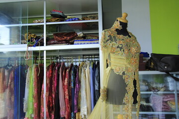 Transparent kebaya dress with brocade and beaded ornaments displayed on a mannequin.