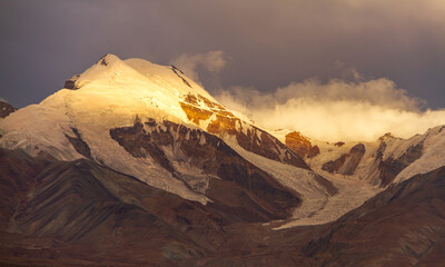 Naklejka premium Golden Sunlight on Snowy Mountain Peak – Sacred Moment in Nature, China