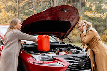 Two Women Refueling Car with Gas Can on Roadside in Autumn – Emergency Fuel Shortage Situation During Travel