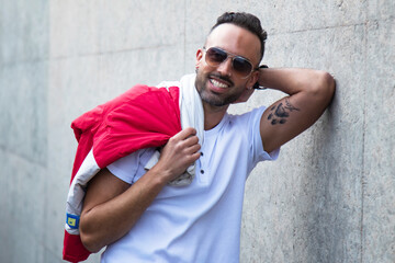 Naklejka premium handsome man wearing jacket and sunglasses posing on the wall