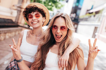 Two young beautiful smiling hipster female in trendy summer white t-shirt and shorts clothes. Sexy...