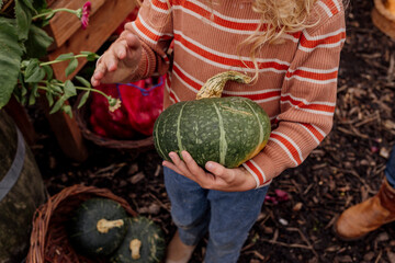 Child holding zucchini in a basket at a local farmers market