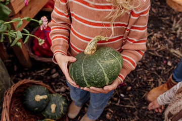 Child holding zucchini in a basket at a local farmers market