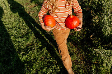 Toddler walking with pumpkins on a sunny day