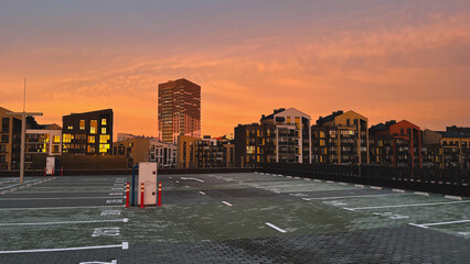 Sunset view over an empty parking lot with silhouetted buildings