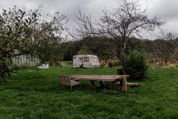 Rustic garden with wooden table and caravan in grassy field