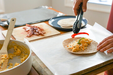 Woman adds red pepper to cheese and eggs for meal prep breakfast