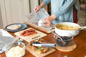Woman in yoga pants and top wraps burrito for meal prep
