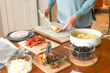 Woman in yoga top and pants adds eggs to breakfast burrito