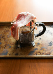 Raw slices of bacon over French press coffee maker