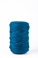 Blue t-shirt yarn spool, vertical image on white background, simple and artisanal style with copy space. Concept of diy textile crafts and creative home