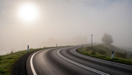 Fototapeta premium Scenic view of a winding road disappearing into the fog with a sunlit sky above the horizon