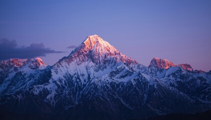 Majestic snow-capped mountain range illuminated by the warm light of dawn or dusk, showcasing vibrant oranges and pinks against a calming blue sky and providing a serene,