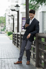 Young man smiling while using mobile phone outdoors