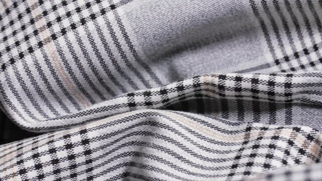 Black and grey glen plaid trouser fabric shows soft folds in a slow macro pan