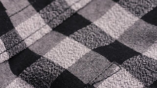 A black and white plaid flannel shirt with a glossy button and soft folds during a slow macro pan.