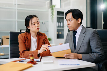 Two professionals discussing legal documents with justice scales on desk in modern office, symbolizing law, consulting