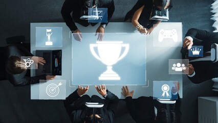 A high-angle view of a business meeting featuring diverse professionals engaging with virtual icons symbolizing achievement and collaboration in a modern workspace. Raster