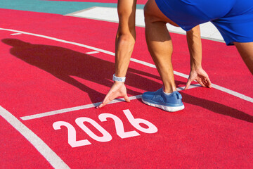 Athlete runner in a pose ready to start on a red treadmill line with the inscription numbers 2026....